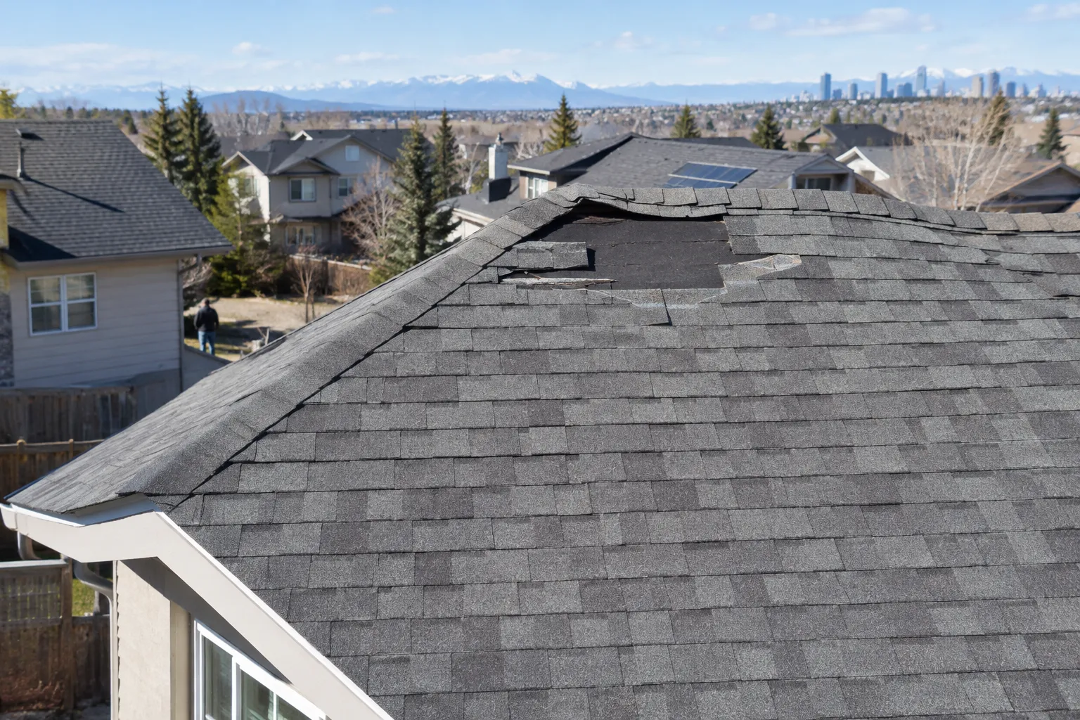A shingle roof with a few shingles missing, showing the underlayment beneath